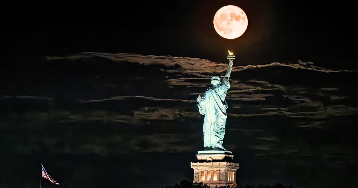 The Sturgeon Supermoon Full Moon breaks through the clouds above the Statue of Liberty in New York City. (Cover Image Source: Getty Images | Diana Robinson Photography)