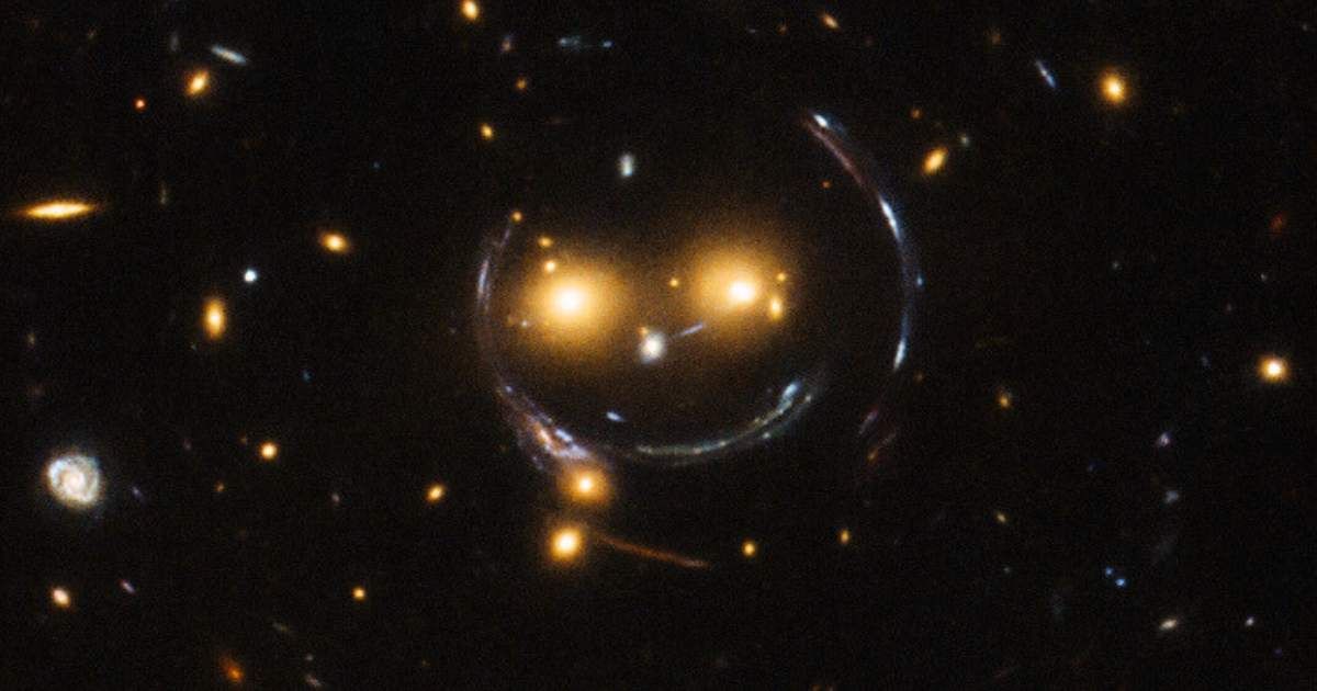Galaxies SDSSCGB 8842.3 and SDSSCGB 8842.4 forming a 'smiling lens' in a photo taken in 2015 (Representative Cover Image Source: ESA/NASA, edited by Starlust staff)