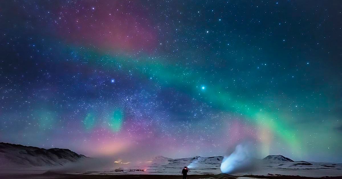 An image of a person enjoying the Northern lights over a geothermal hot spring area, Hverarond, Iceland (Representative Cover Image Source: Getty | Arctic-Images)