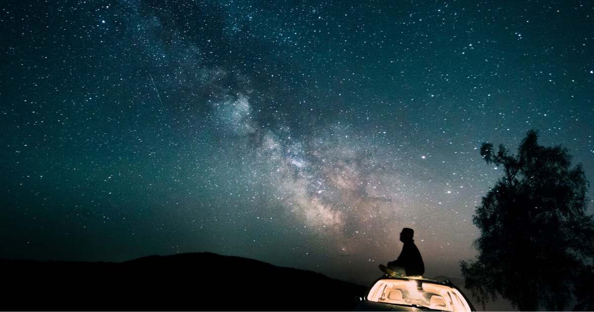 Austria, Mondsee, silhouette of man sitting on car roof under starry sky (Representative Cover Image Source: Getty | Westend61)