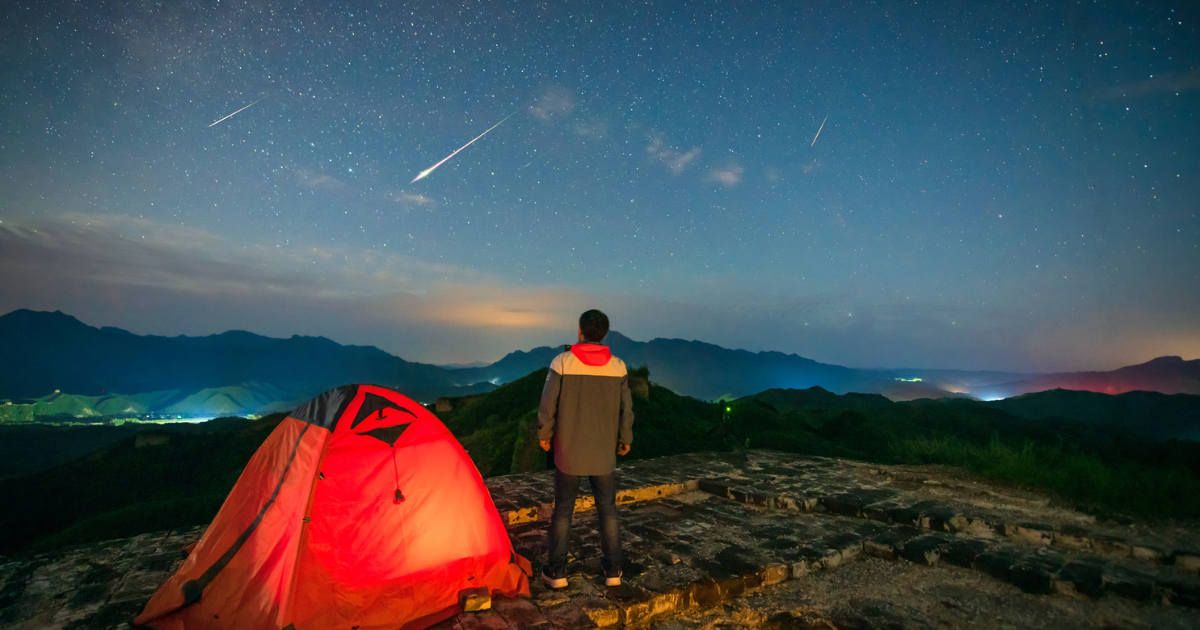 A man watching a meteor shower on the beacon tower of the Great Wall in China (Representative Cover Image Source: Getty | bjdlzx)