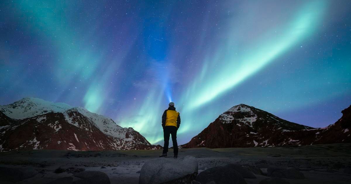 A person admiring the Northern Lights (aurora borealis) in Lofoten, Norway (Cover Image Source: Getty | © Marco Bottigelli)