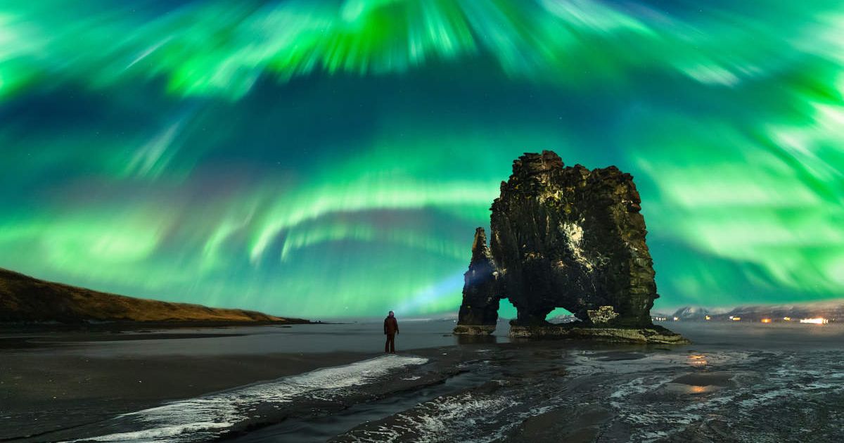 Man watching the Aurora Borealis above the Hvítserkur rock formation, Northwest Iceland, Golden Circle Route, Vatnsnesvegur, Iceland (Image Source: Getty | Juan Maria Coy Vergara)