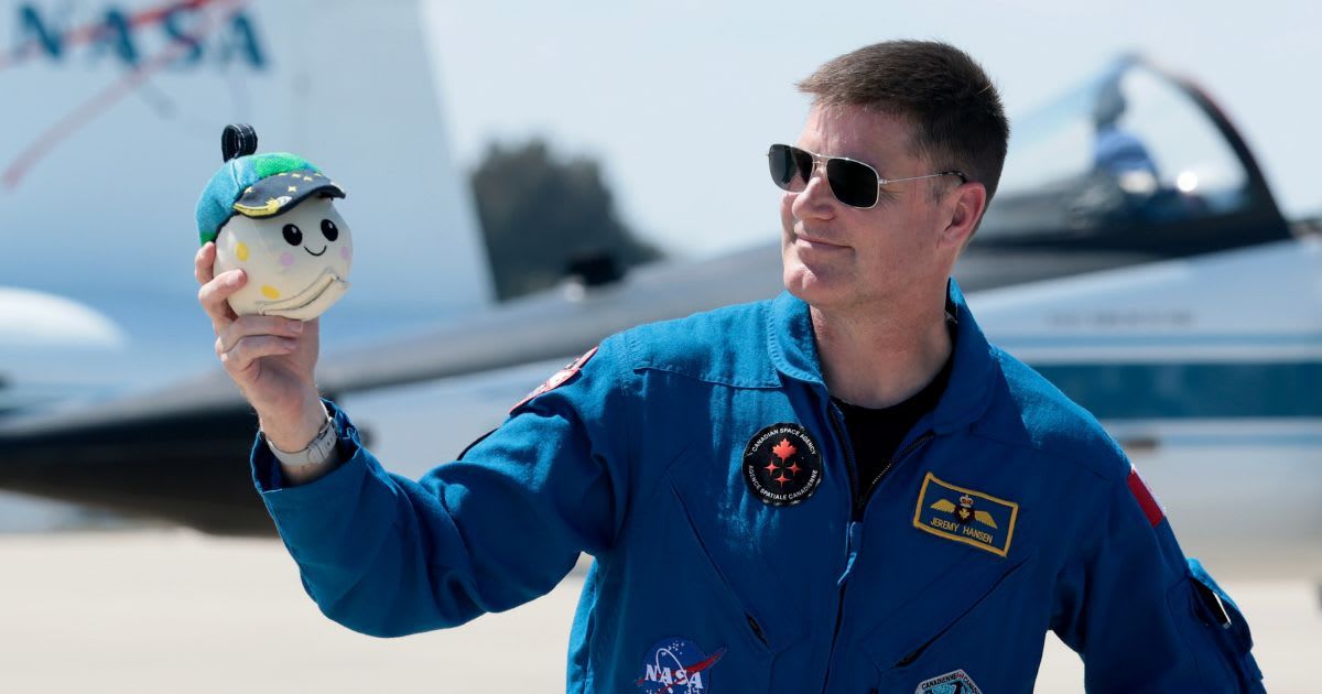 Artemis II mission specialist Jeremy Hansen of CSA holds the “moon mascot” after arriving at Kennedy Space Center. (Cover Image Source: Joe Raedle/Getty Images)