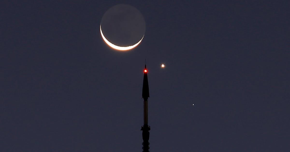 A 6% illuminated Waning Crescent Moon, the planet Venus, and the star Regulus rise together behind One World Trade Center at sunrise in New York City on September 19, 2025. (Cover Image Source: Gary Hershorn/Getty Images)
