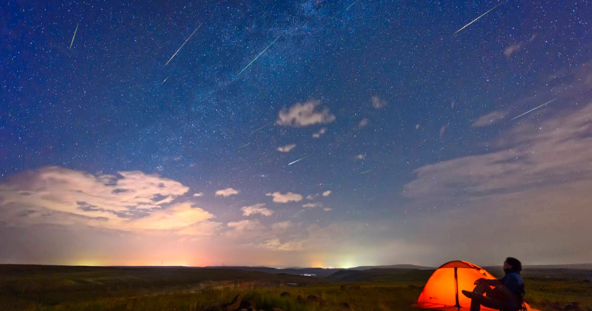 A man watches a meteor shower, sitting beside the edge of his tent. (Representative Image Source: Getty | bjdlzx)