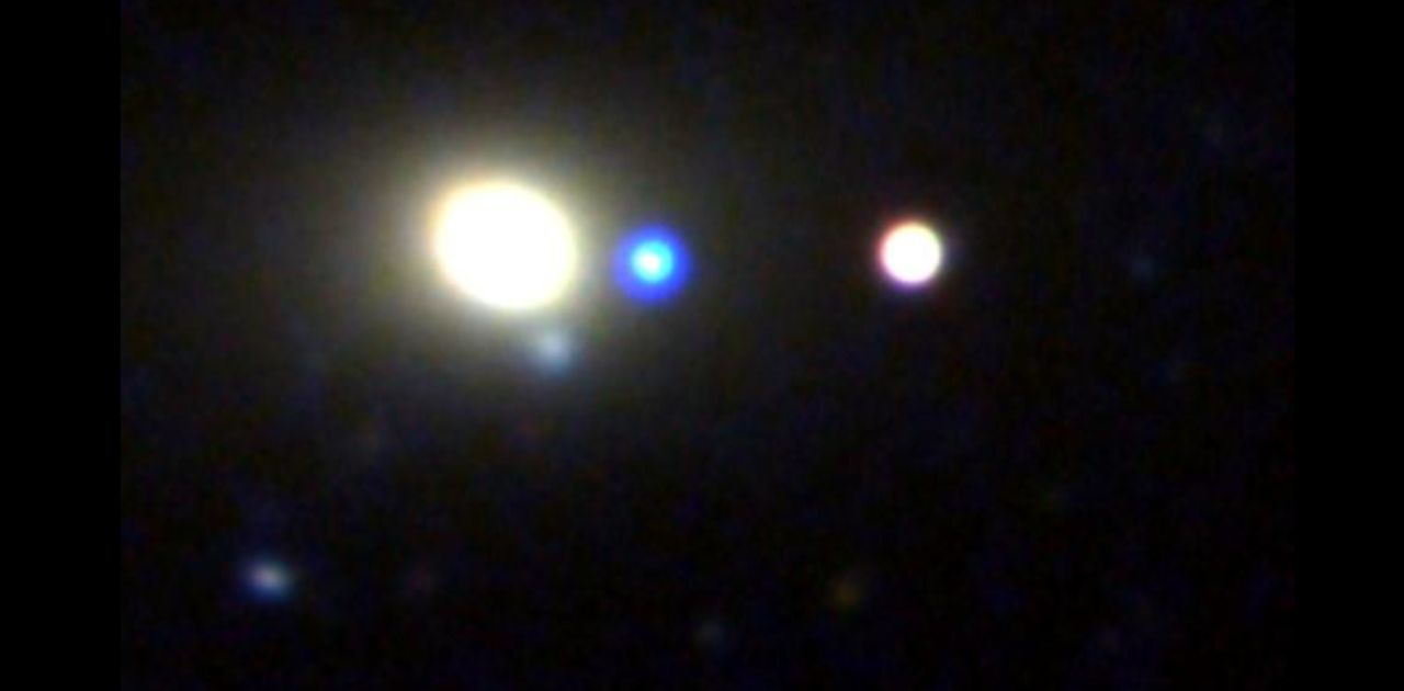 A supermassive black hole revealed itself with a flash of light, shown at the center of this image in blue, as it wandered the edge of a galaxy.