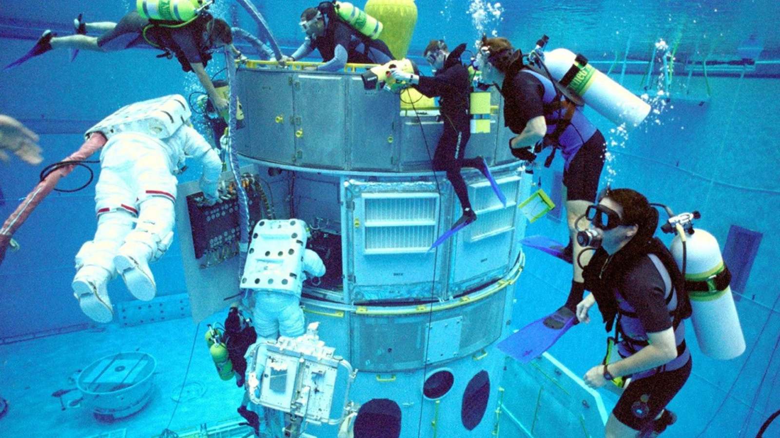 Astronauts train to service the Hubble telescope in a water-filled tank at the Neutral Buoyancy Lab under scuba experts' guidance, June 21, 1999.