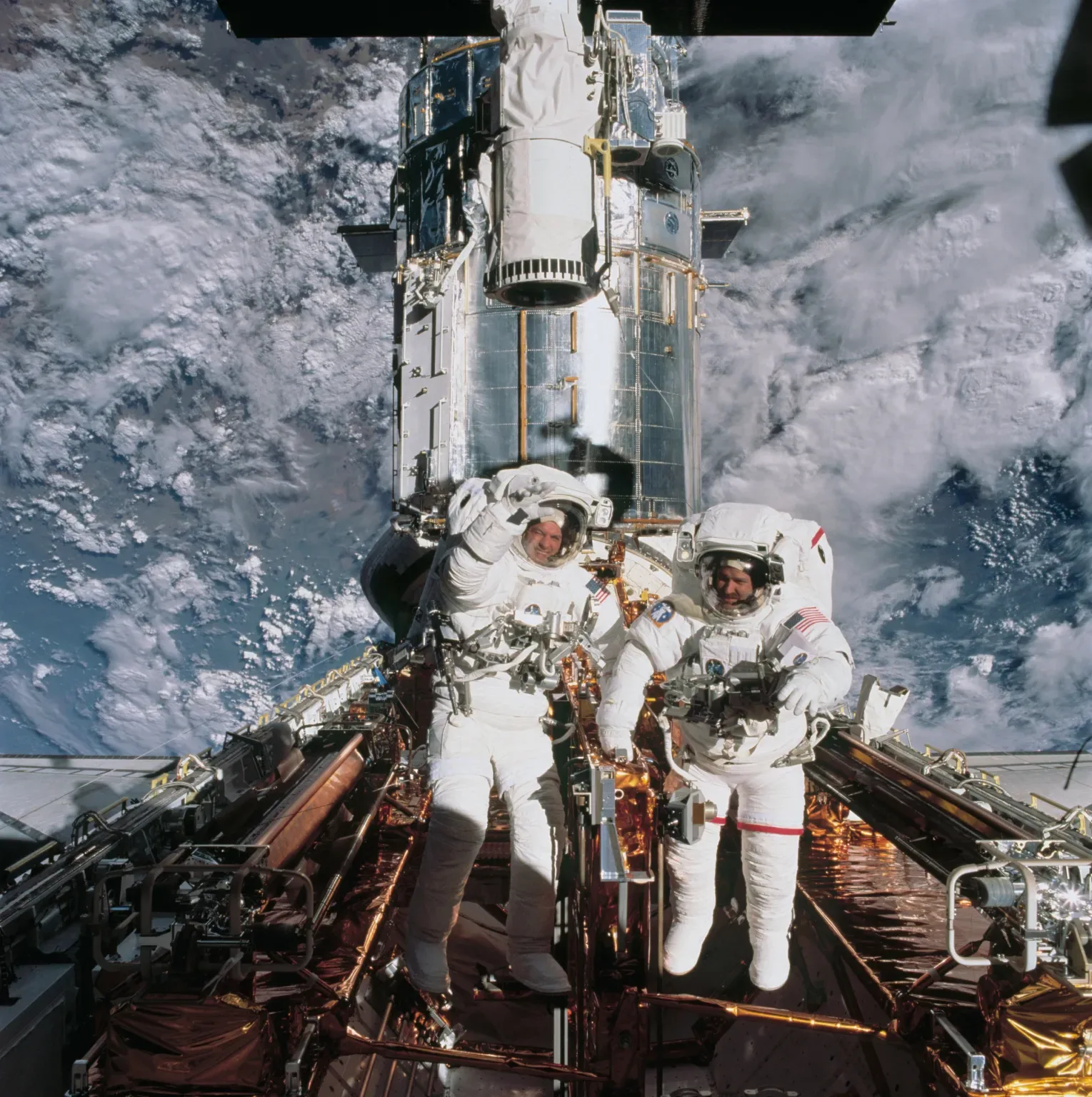 Astronauts John M. Grunsfeld (right) and Richard M. Linnehan are photographed near the Hubble telescope temporarily parked in the Space Shuttle Columbia’s cargo bay during STS-109 mission, March 2002.