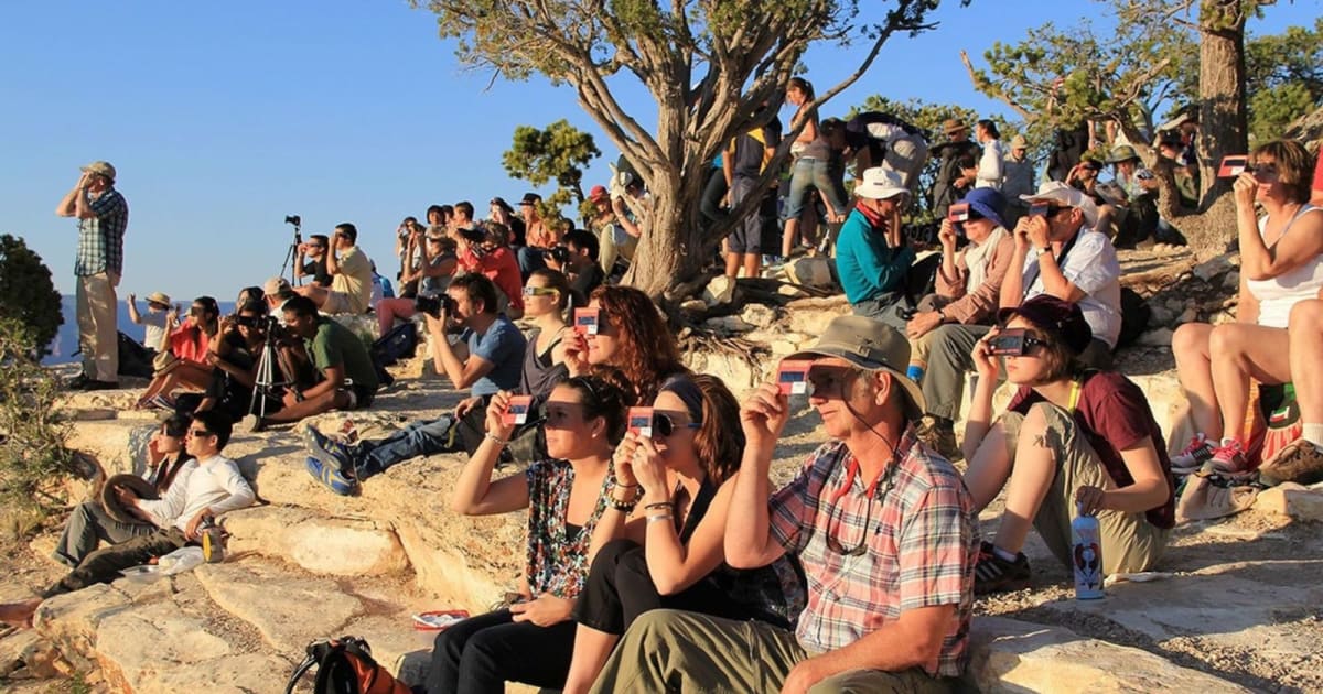 A crowd uses handheld solar viewers and solar eclipse glasses to safely view a solar eclipse. — (Cover Image Source: NASA/National Park Service)