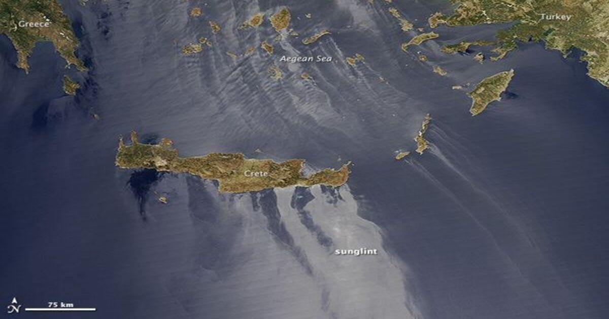 Sunglint over the Aegean Sea near Crete. Sunlight reflecting off the water creates the bright, mirror-like pattern visible around the island. (Image Source: NASA Earth Observatory image by Jesse Allen, using MODIS data)
