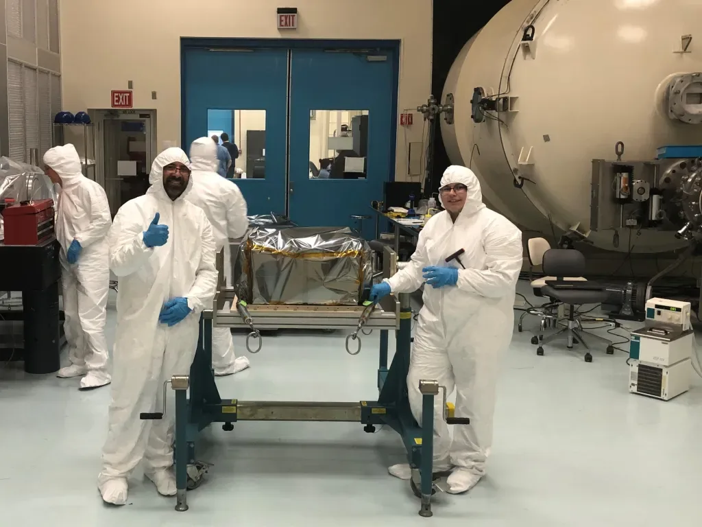 Starburst Principal Investigator Dr. Daniel Kocevski, left, and Integration and Test Engineer Elise Doan, right, pose with the StarBurst instrument after it was unboxed in the cleanroom environment at NASA Marshall. The Naval Research Lab transferred the instrument to NASA in early March. Image Credit: NASA/Davy Haynes