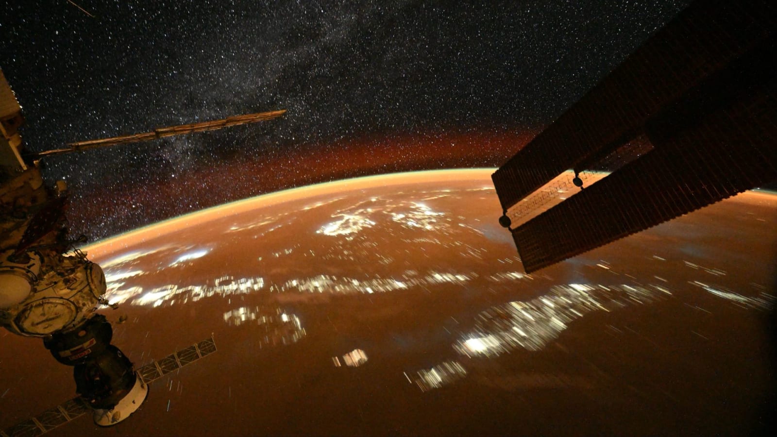 The Progress 95 spacecraft is visible on the left corner as the International Space Station transits over Earth.